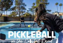 Image shows a woman with long dark hair that is in a pony tail. She is on a pickleball court, playing pickleball. Text reads: Pickleball in the Coastal Bend - The Ultimate Guide